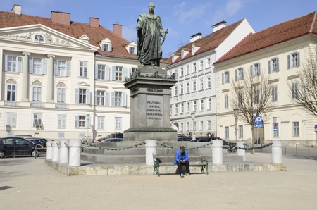 Men reading at a bench in front of Monument of emperor Franz I at Plaza of the Liberty  in Graz,  the capital of federal state of Styria, Austria.のeditorial素材