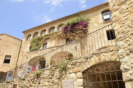 Beautiful stone house with flowers on its wall in the medieval village of Pals, located in the middle of the Emporda region of Girona, Catalonia, Spain.のeditorial素材