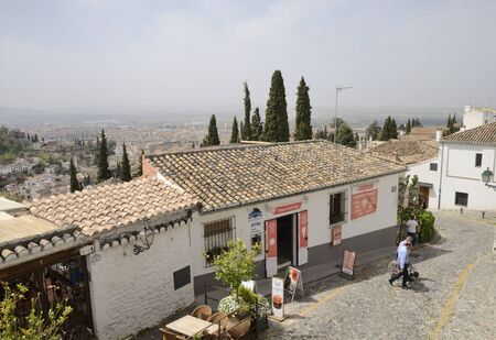 A few people in street downhill seen form the viewpoint of Saint Nicholas  in the Albaicin district...