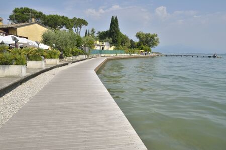 Sirmione, Italy - August 7, 2014: Wooden path along the lake in Sirmione, located in the lake Garda, Italy.のeditorial素材