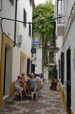 Marbella, Spain - August 12, 2019: People at exterior restaurant in narrow alley of the old town of Marbella, a city of the province of Malaga, Andalusia, Spain.のeditorial素材