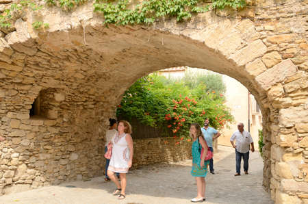 Peratallada, Spain - July 25, 2017: People under stone arch at cobbled street of the medieval village of Peratallada, located in the middle of the Emporda region of Girona, Catalonia, Spain.のeditorial素材