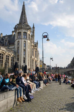 Ghent, Belgium - March 31, 2019: People sitiing at the banks of the canal in the Old Town of Ghent, the capital of the East Flanders province in Belgium.のeditorial素材