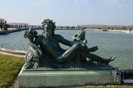 Versailles, France - March 5, 2022: One of the statue in Lake of the gardens in the Palace of Versailles, France.のeditorial素材