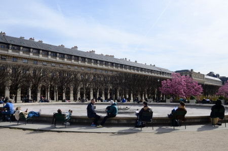 Paris, France - March 16, 2023: People on chairs for a rest around a pond without water in the gardens of the Royal Palace in Paris, France.のeditorial素材