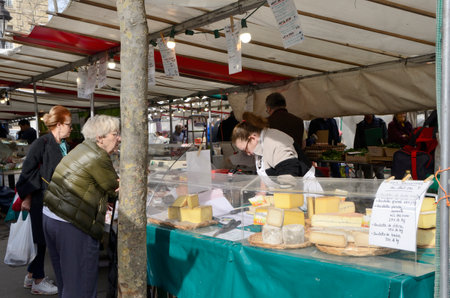 Paris, France - March 17, 2023: People buying cheese at street market in Paris, France.のeditorial素材