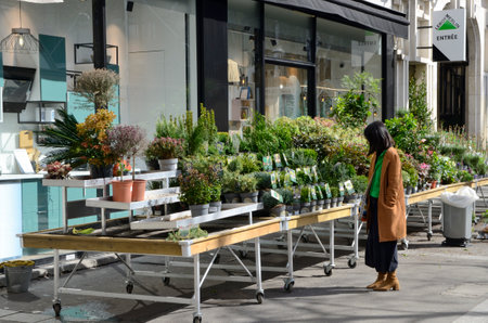 Paris, France - March 18, 2023: Woman looking at the plants of street stall of flowers store in Paris, France.のeditorial素材