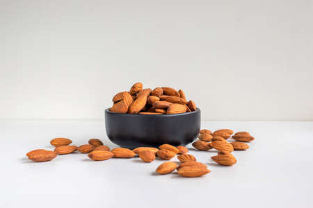 Almonds in a black bown on white tabel background.の写真素材