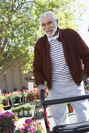 Elderly man with walking frame in garden centerの写真素材
