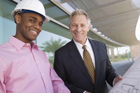 Businessman looking at blue prints with construction worker, portraitの写真素材
