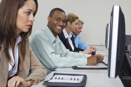 Group of business people using computers in classroom, side view