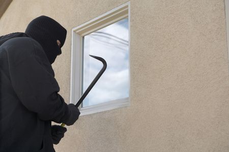 Burglar using crowbar to break into houseの写真素材