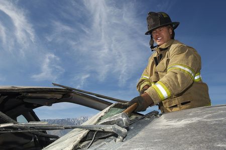 Firefighter hitting crashed car with hammerの写真素材