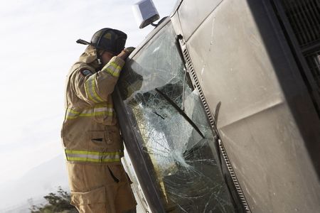 Firefighter looking into crashed carの写真素材
