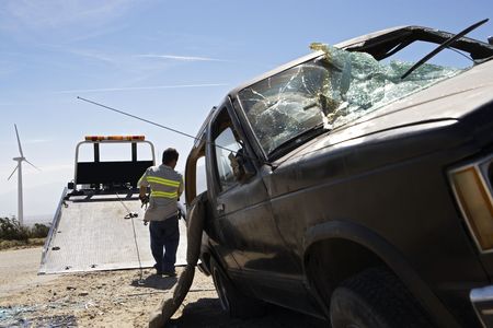 Man preparing to lift crashed car onto tow truckの写真素材