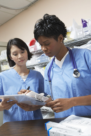 Female doctor and nurse in hospital doing paperwork
