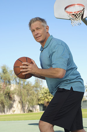 Senior man playing basketball on outdoor courtの写真素材
