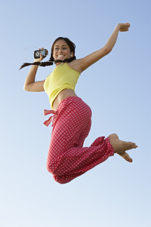 Young woman jumping with mp3 player in handの写真素材