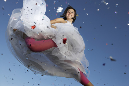 Portrait of young woman in wedding dress jumpingの写真素材