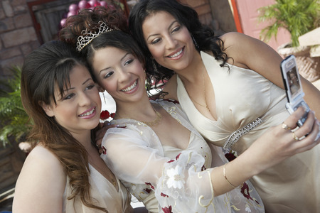 Bride taking self-portrait with two friends using mobile phoneの写真素材