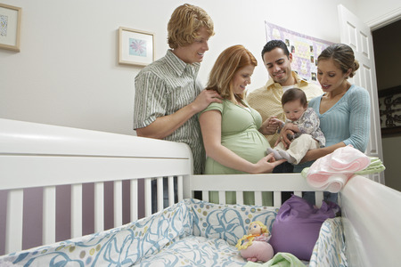 Two couples and baby (1-6 months) by cradle
