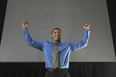 Business man speaking at conference, arms raised