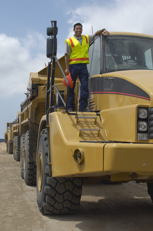 Worker standing on truck at landfill site, portrait