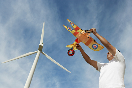 Man holding airplane kite at wind farm