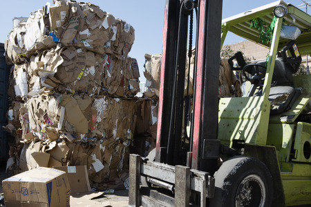 Stacks of cardboard boxes in recycling centre and forklift truck