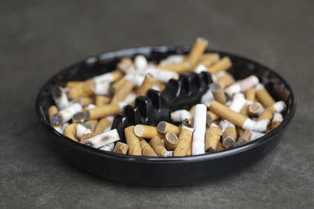 Full ashtray of cigarettes on table, close-up