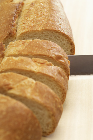 Close-up of knife slicing baguette
