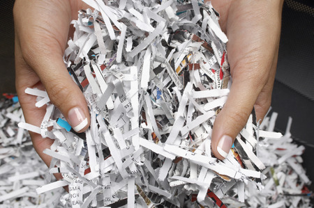 Woman holding heap of shredded paper, close-up of hands