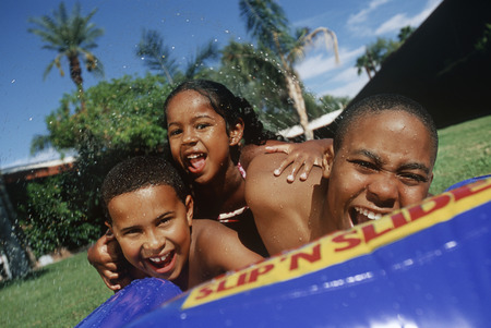Two boys (7-9) and girl (5-6) playing in wading pool