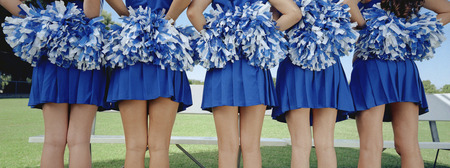 Five cheerleaders in row, back view, mid section