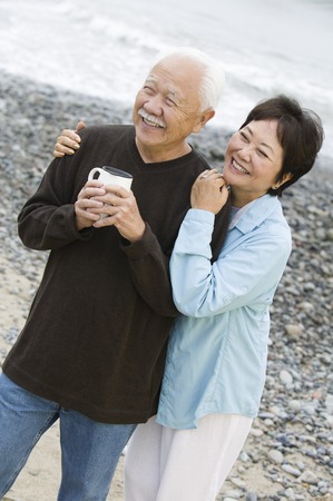 Senior couple at beach looking at camera