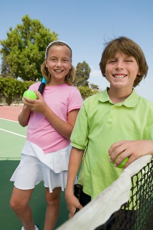 Brother and Sister at Tennis Netの写真素材
