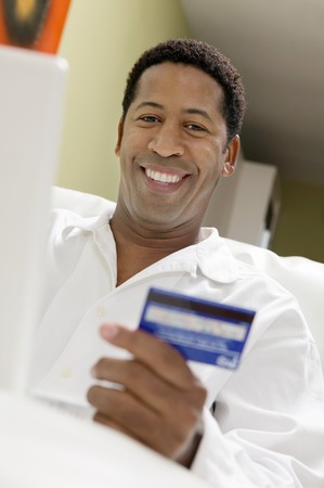 Man Using Credit Card to Make Purchase with Laptopの写真素材