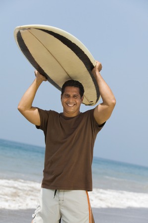 Man Carrying Surfboard Over His Headの写真素材