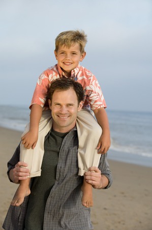 Father with Son on Shoulders at Beachの写真素材