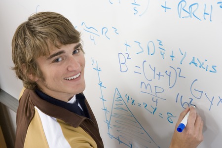 Male student writing maths equations on whiteboardの写真素材