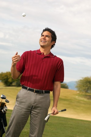 Golfer Holding Putter Tossing Golf Ball in Airの写真素材