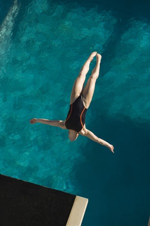 Young woman diving into swimming poolの写真素材