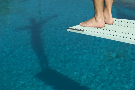Male swimmer standing on diving boardの写真素材