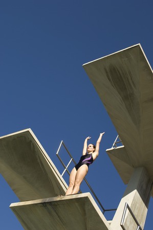 Female swimmer standing on diving boardの写真素材