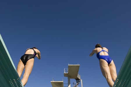 Two female swimmers standing on diving boardの写真素材