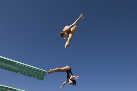 Two women diving from diving boardの写真素材