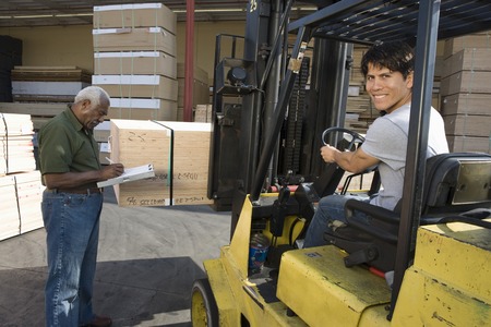 Senior warehouseman and mid-adult forklift truck driver