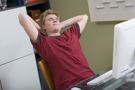 Teenage boy (16-17) in front of computer, stretching