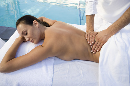 Woman having massage by swimming poolの写真素材