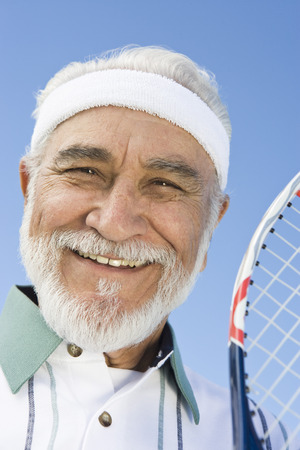 Senior man holding tennis racket, portraitの写真素材